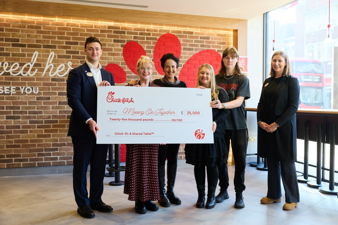 An image of Chick-fil-A Kingston Owner-Operator Connor Ashford and a Chick-fil-A Shared Table check, alongside representatives from the Moving On Together charity.